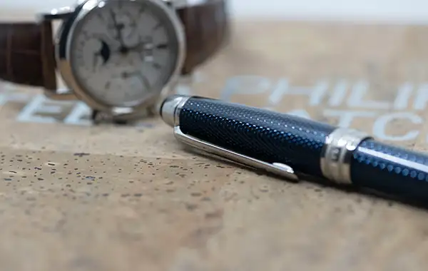 Photo of a pen and a watch in the background
